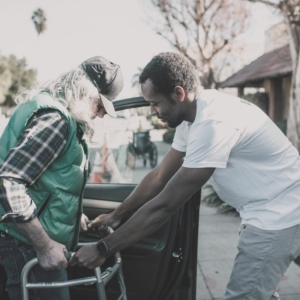 Un jeune homme aide une personne handicapée à sortir d'un véhicule